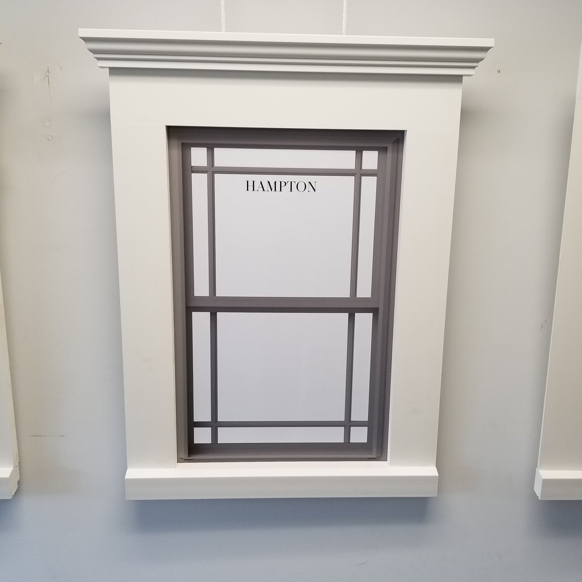 Window with decorative frame and 'Hampton' branding on a light gray wall.